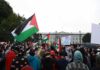 Concert Turns Political In One Gesture Crowd holding flags and signs outside a fenced government building