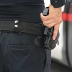 Father Pulls Gun And Community Demands Action Officer gripping a holstered handgun on a duty belt