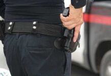 Officer gripping a holstered handgun on a duty belt