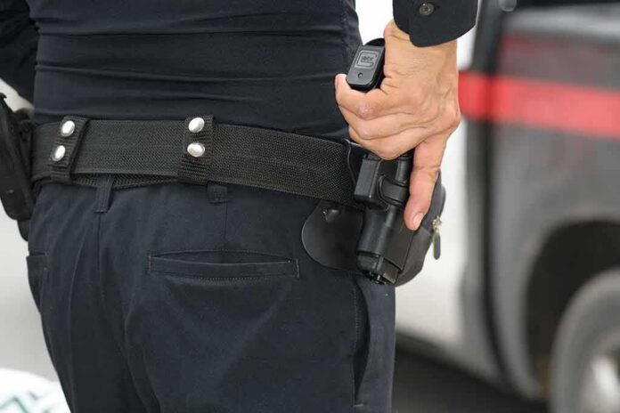 shutterstock_305805866 Officer gripping a holstered handgun on a duty belt