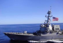 American Warships Targeted, U.S. Forces Respond Naval destroyer sailing on open sea with flag flying