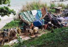 makeshift shelter near a beach with tarps and clothes drying