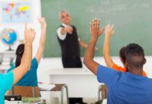 OnlyFans Twist Torches School Job Students raising hands in a classroom while teacher points