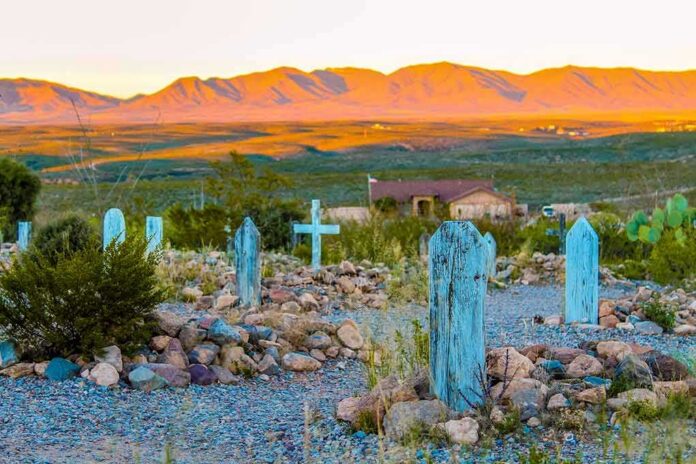Desert cemetery with weathered blue wooden grave markers at sunset