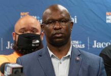 Man in suit and glasses at a press conference
