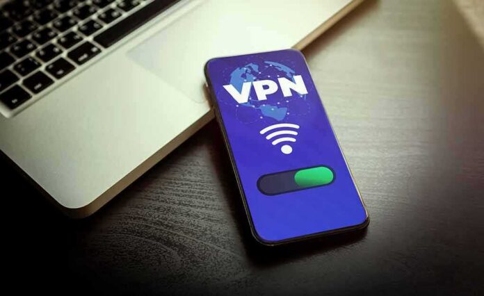 shutterstock_2033310410 Smartphone showing VPN app beside a laptop