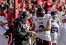 Mississippi State football coach and quarterback review play card on sideline