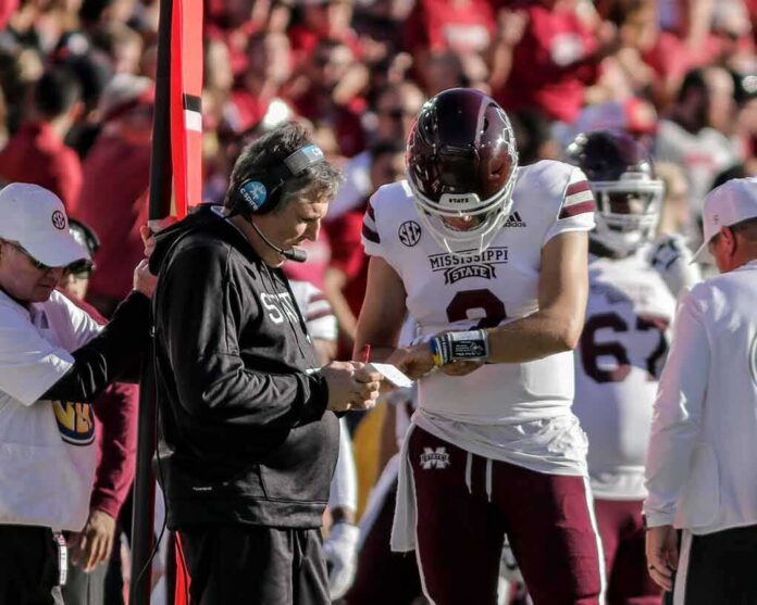 Mississippi State football coach and quarterback review play card on sideline
