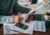 $90 Payments Are Heading to Millions of Seniors Person reviewing bills with calculator at cluttered desk