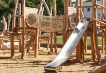 wooden playground with rope tunnel and metal slide