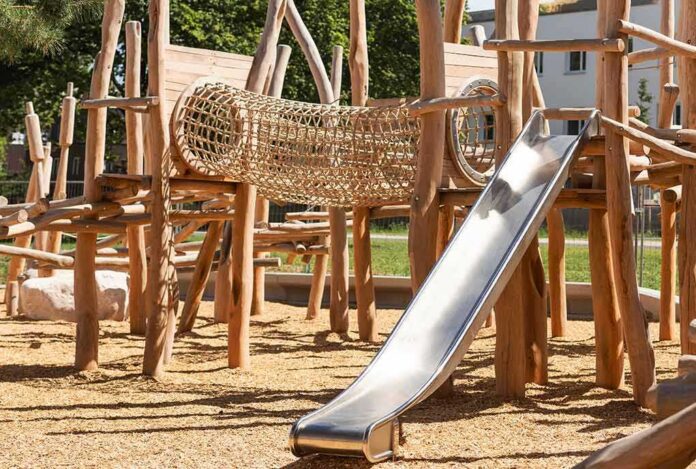 shutterstock_2288277991 wooden playground with rope tunnel and metal slide