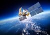 A satellite equipped with solar panels orbiting above the Earth