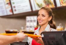 Smiling cashier handing food trays to a customer